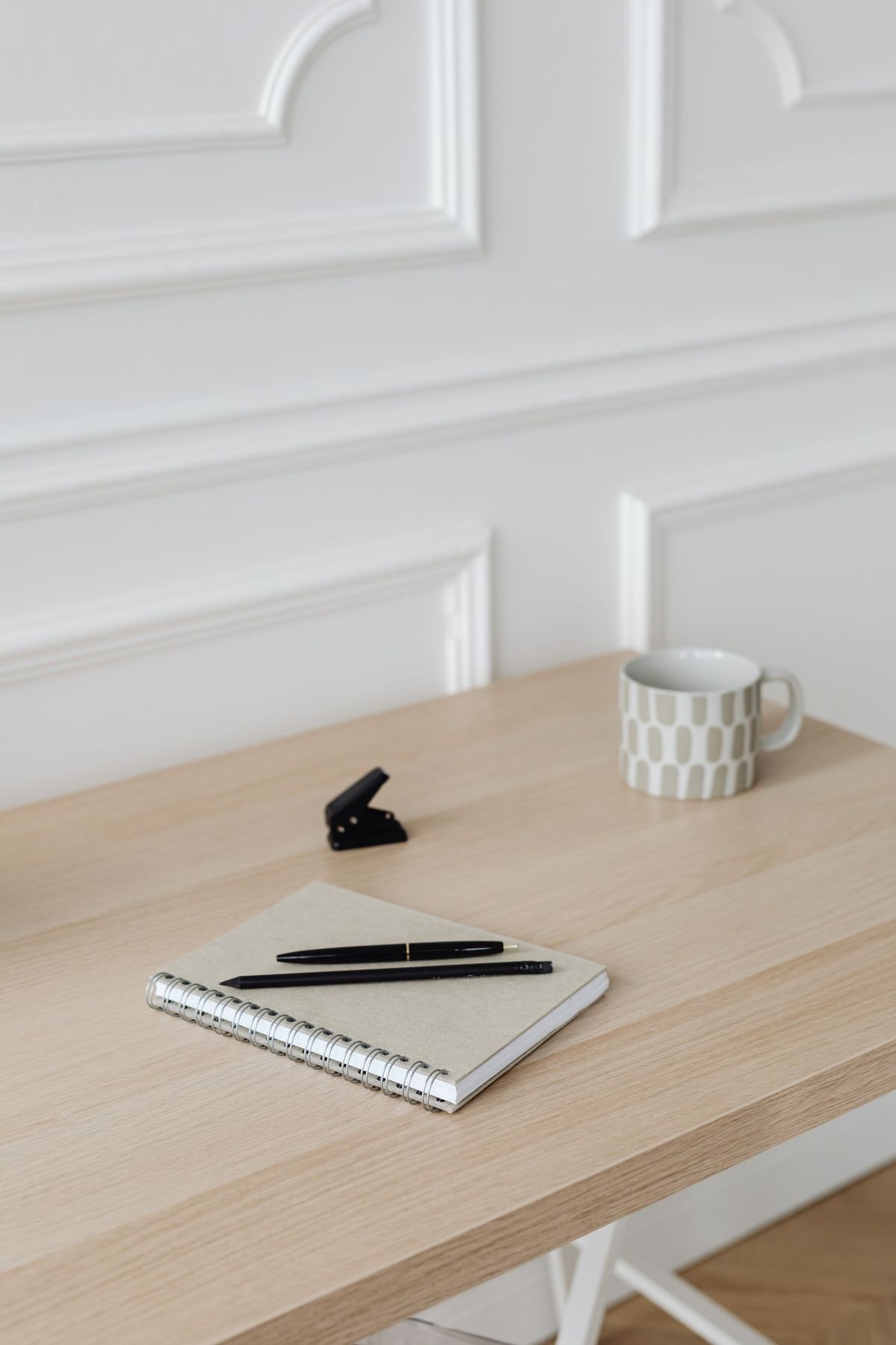 A notebook, pen and coffee mug on a wooden desk